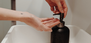 Person washing hands using soap dispenser
