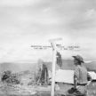 A member of the Worcestershire Yeomanry views an amusing roadsign beside an ancient standing stone at 'Stonehenge Camp' on the Imphal to Kohima road. The sign reads 'Worcester, 5100 miles & No Way Out' and 'Tokyo, 2,800 miles & Way Out', November 1944.