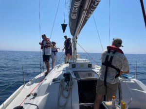 Crew stand on sailing boat in the sun