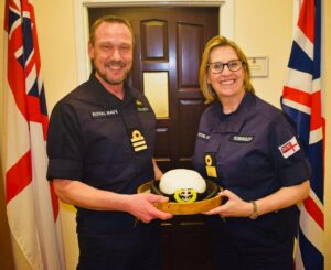Commander Michael Howarth presenting Commodore Robinson with a Royal Navy tricorn hat cake