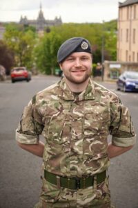James stands outside of 603 Squadron in Edinburgh and smiles to camera