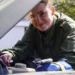 Rachel peers through the car bonnet as she works on the engine