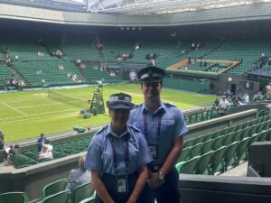 Officer Cadets Byres and Campbell from Universities of Glasgow and Strathclyde Air Squadron standing together in front of the All England Club tennis court.