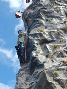 A Junior Cadet turns and smiles for the camera during a wall-climbing activity.